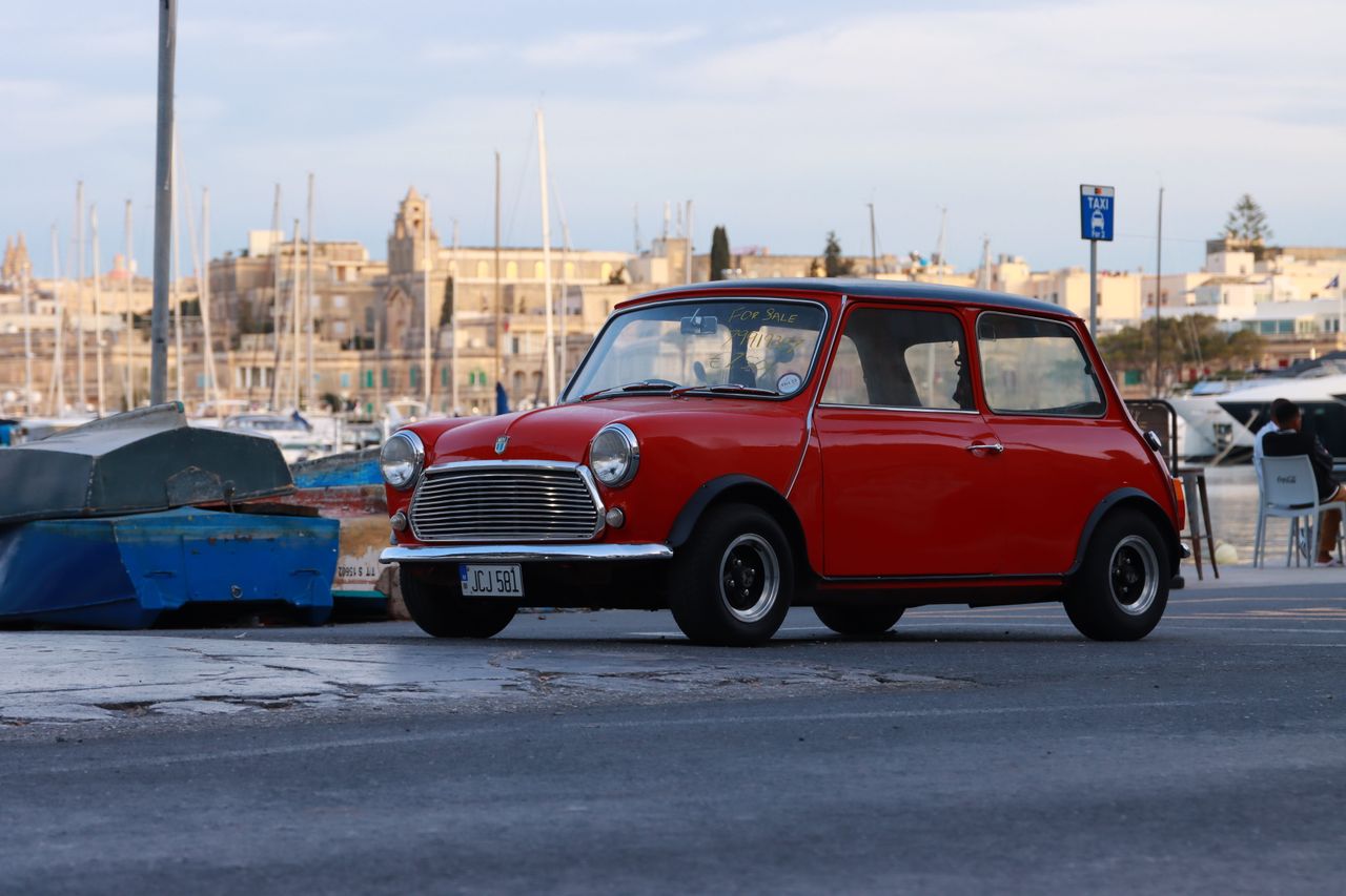 A nostalgic red Mini Morris parked by the waterfront in historic Valletta, Malta.