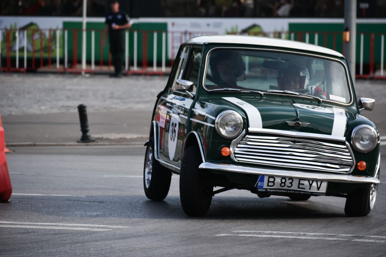 Male driving on vintage automobile with round headlights with numbers and stickers on racing track